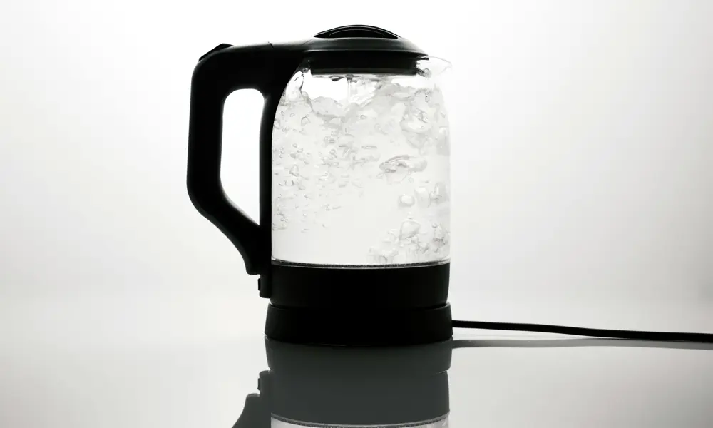 A transparent electric kettle boiling water which is bubbling inside. 