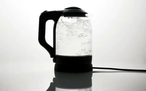 A transparent electric kettle boiling water which is bubbling inside.
