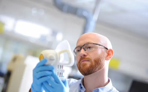 A person holding an Owlstone Medical device that captures breath samples.
