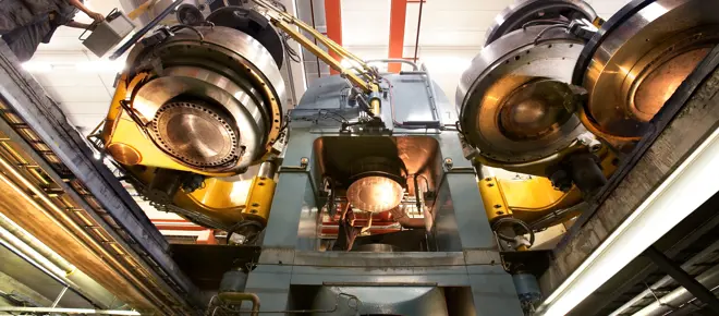 A large diamond press machine inside, with a person operating it towards the left. 