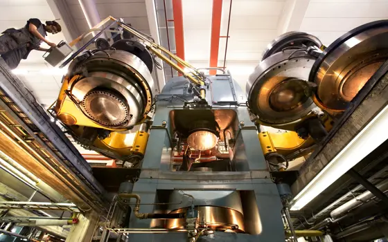 A large diamond press machine inside, with a person operating it towards the left. 