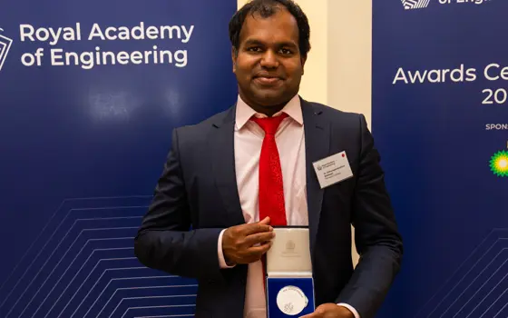 Dr Sabesan Sithamparanathan standing with the Sir George Macfarlane medal, at the Royal Academy of Engineering awards ceremony.