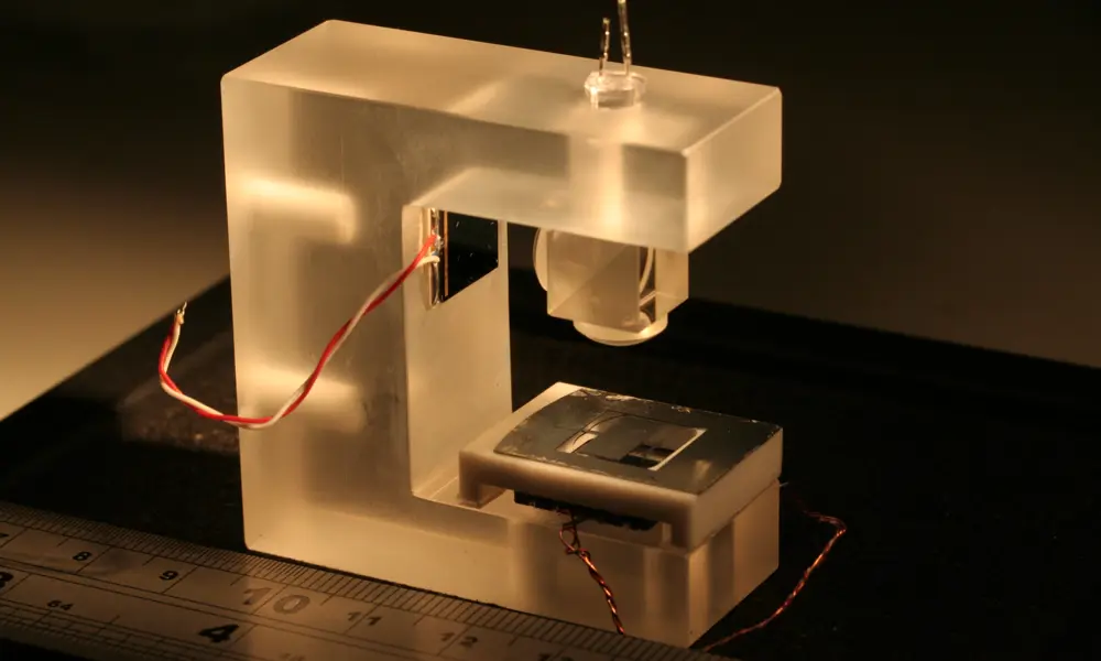 The gravimeter placed next to a ruler for scale. The device includes an LED light source, micro-electromechanical systems and a photodiode (i.e. a shadow sensor).