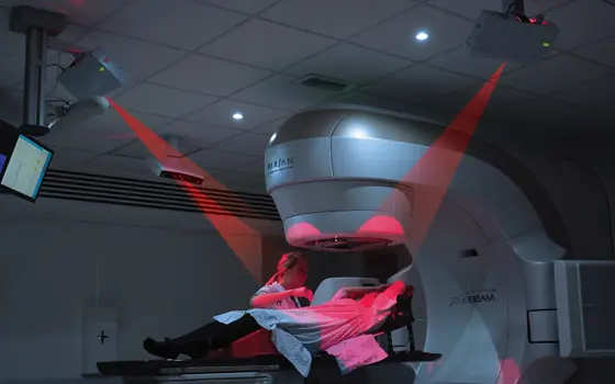 A patient lying under a radiotherapy machine that is being used with the AlignRT system.