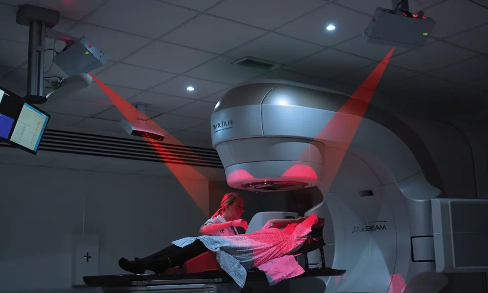 A patient lying under a radiotherapy machine that is being used with the AlignRT system.