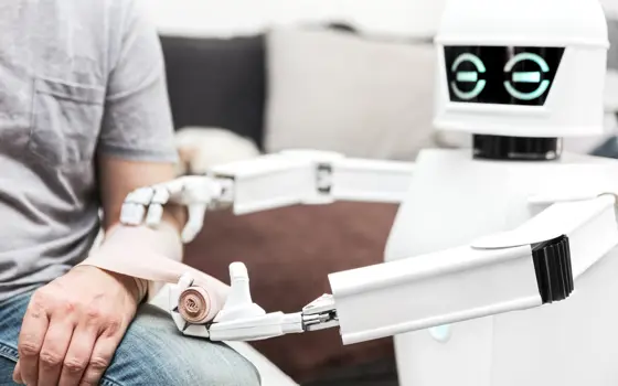 A small white robot bandaging up a person's forearm.