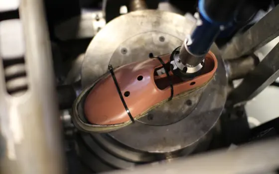 A combat boot attached to a metal leg strapped onto a metal plate.