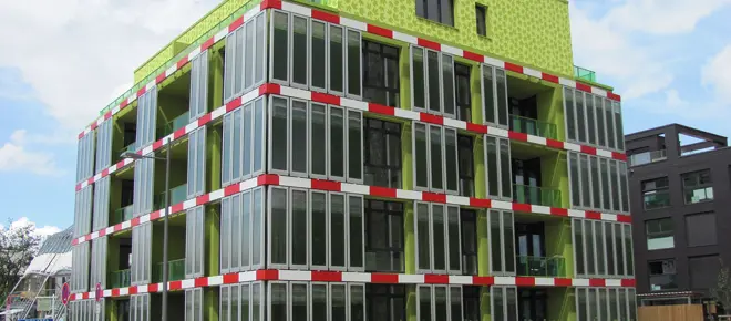 An apartment with green microalgae tanks built into the outside of the building.