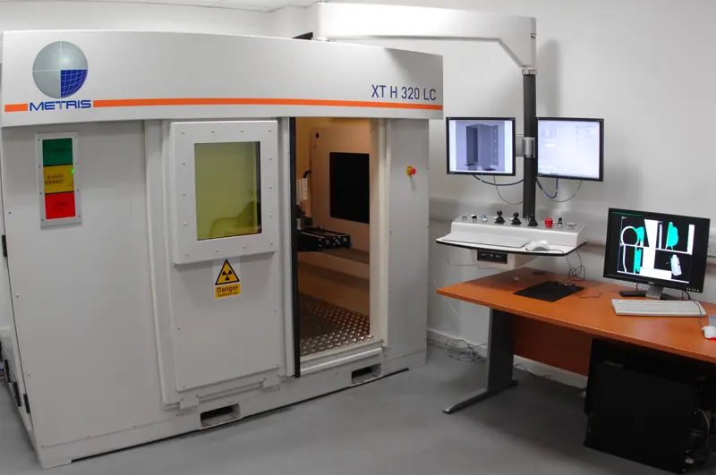 A micro-CT scanner in a radiation-protected room with a computer screen outside.