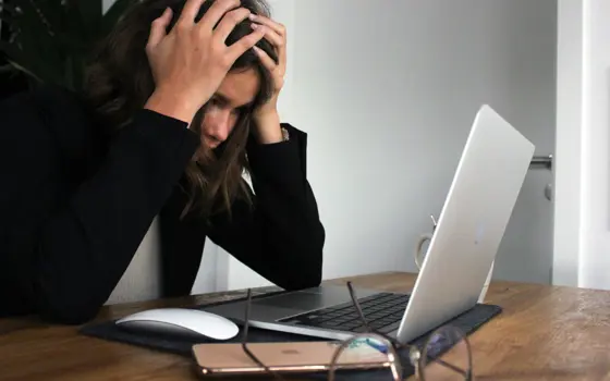 A woman in black long sleeve shirt covering her face with her hands.