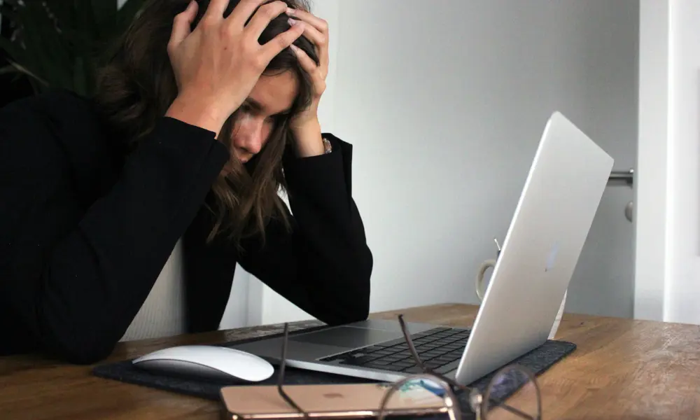 A woman in black long sleeve shirt covering her face with her hands.
