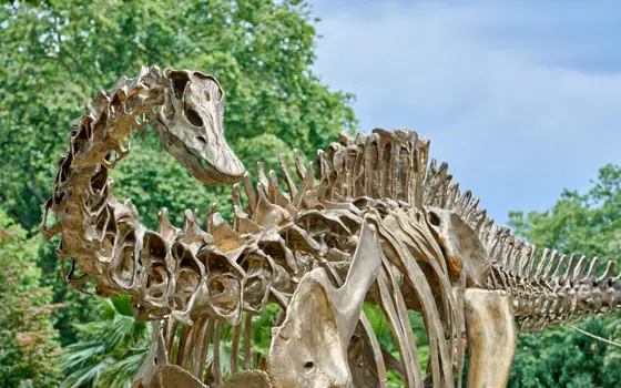 A bronze dinosaur in a garden on a sunny day