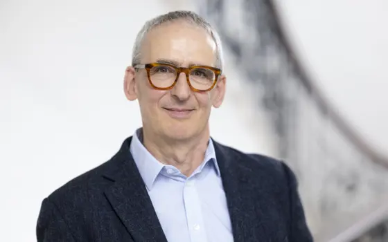 A man with tortoise shell glasses smiling at the camera.