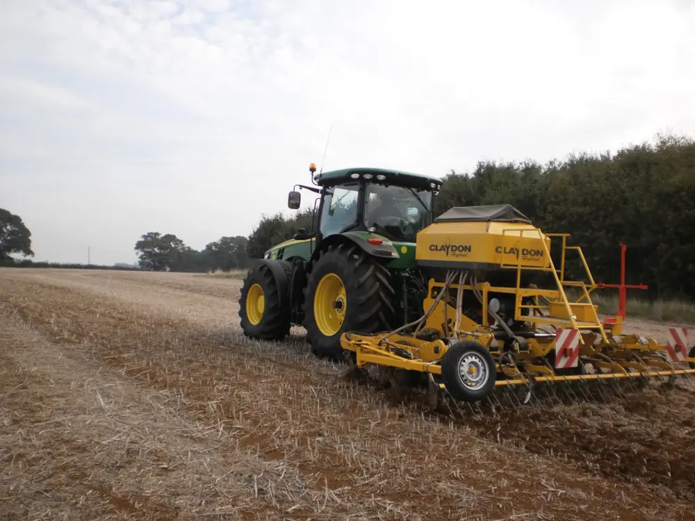 A photograph of a tractor in a field with a plough attached to the back of it.
