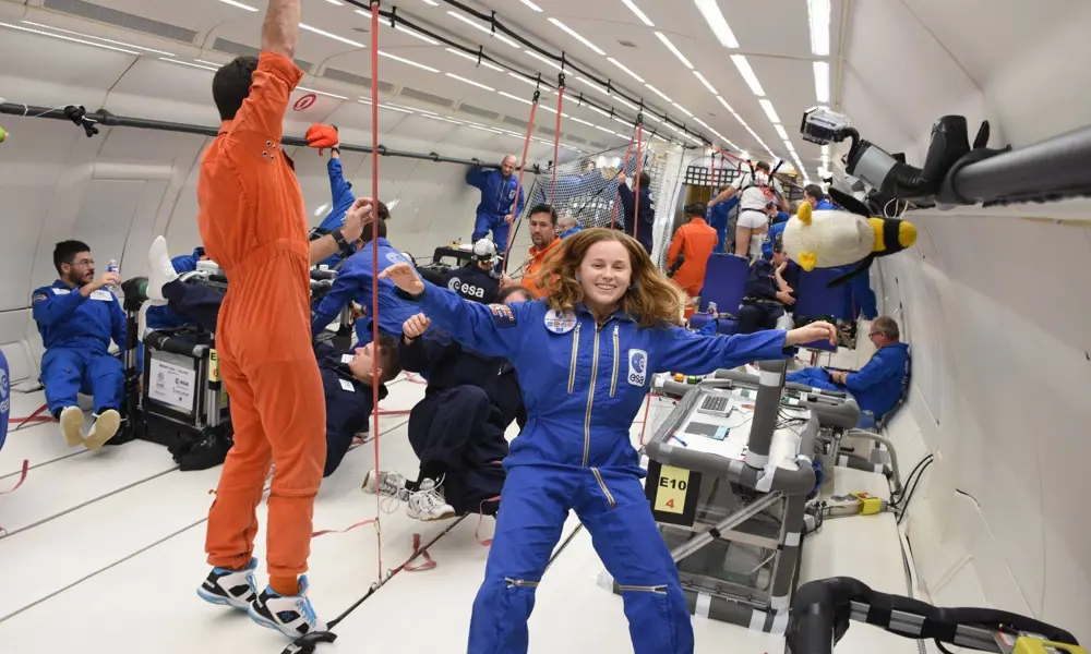 A woman floating in a space suit with her hair spread around her in the hold of a plane during parabolic (zero gravity) flight