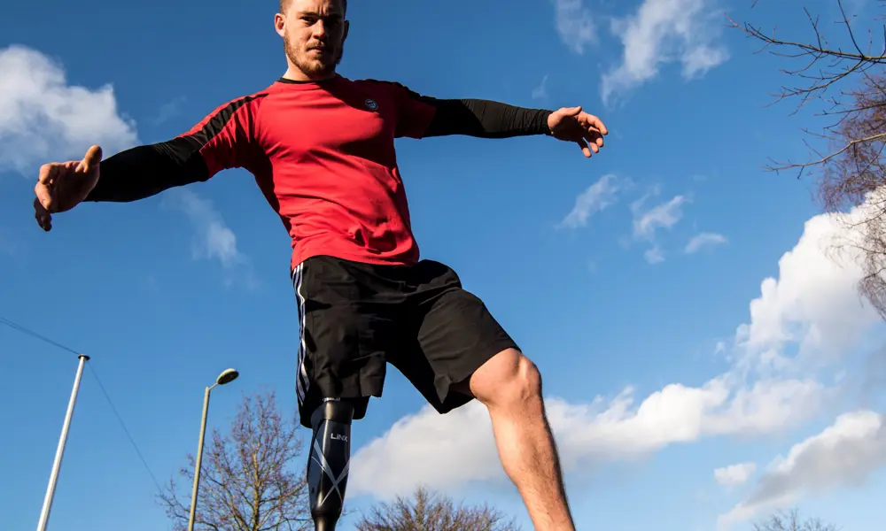 A male with a prosthetic leg wearing sports gear.