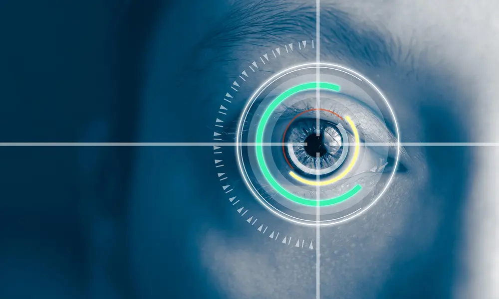 A blue tinted close up photo of an eye with a pattern of overlaid concentric white, green, yellow and red circles on it