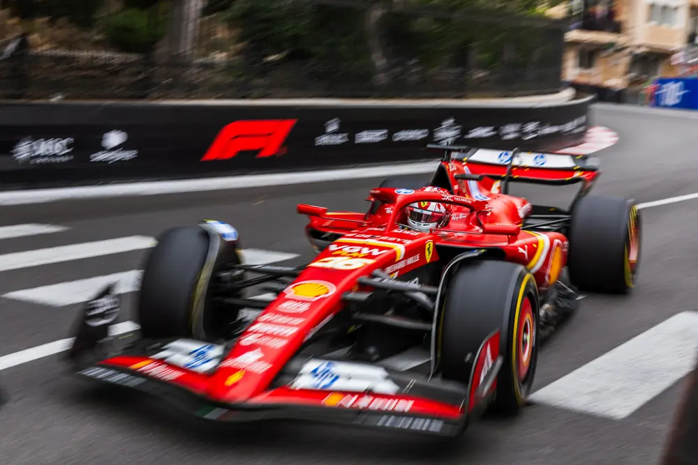 A red Formula 1 car with the background blurred to indicate it moving quickly.