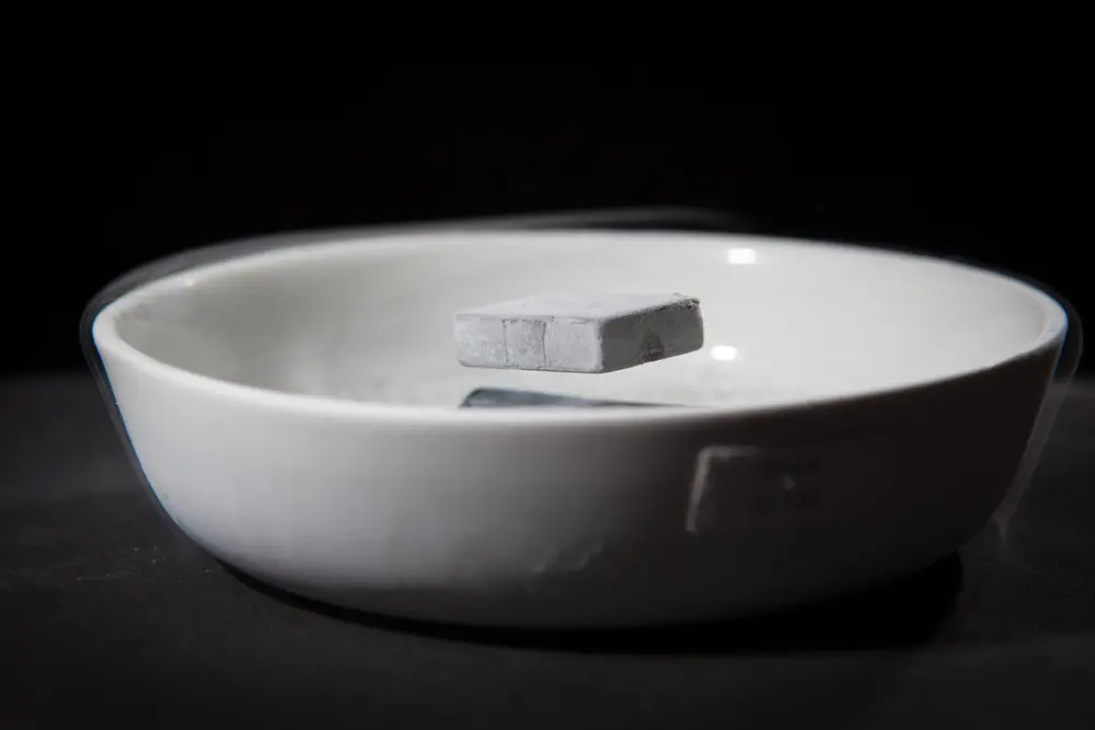 A solid chunk of grey material floating above a bowl with wispy, smoke-like liquid nitrogen around it