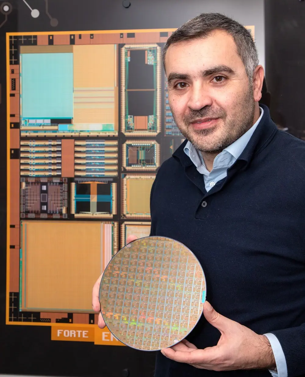 Themis Prodromakis holding a circular silicon wafer patterned with memristors.